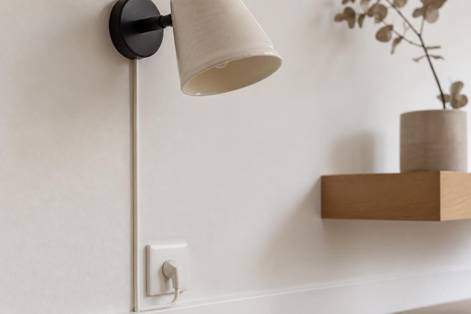 Gaine textile ivoire camouflant câble applique murale sur mur blanc