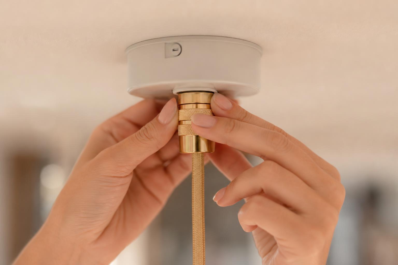 Gros plan branchement connecteur DCL doré dans rosace plafond blanc